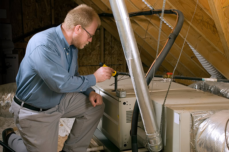 Furnace Maintenance and Winter Energy Saving Tips. Photo of a technician installing a heating system in a home. Photo of a technician installing a furnace.
